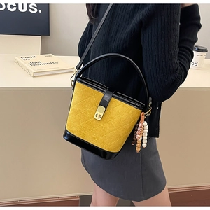 Détail du sac seau rétro matelassé jaune avec base en cuir noir contrastée élégante