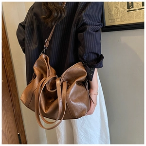 Brown large capacity leather tote bag styled on model in vintage indoor setting