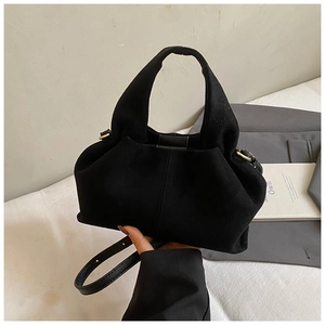 Detail of black matte suede shoulder bag with leather handle and minimalist design