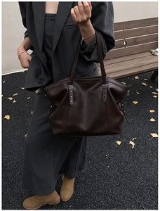 Detail of dark brown leather tote bag with star metal hardware and slim handles