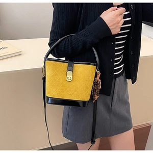 Détail du sac seau matelassé jaune avec base en vernis noir et fermoir rotatif doré