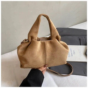 Detail of light brown suede cloud bag with pleated texture and stylish metal ring buckle