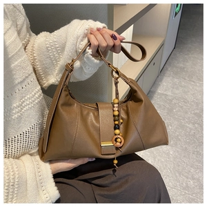 Detail of brown leather tote with metallic buckle and decorative wooden bead charm