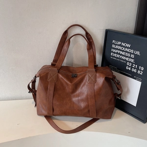 Vintage large capacity dark brown leather travel bag with adjustable strap on white table