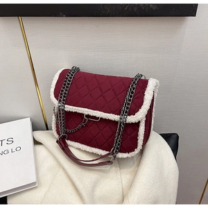 Detail of burgundy quilted velvet bag featuring white shearling trim and metal chain strap