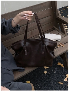 Close-up of deep brown tote bag with silver studs on an autumn park bench