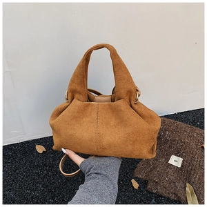 Detail view of caramel suede handbag with textured folds and magnetic closure feature