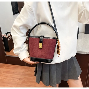 Détail du sac seau matelassé bordeaux avec fermoir doré et pendentif en perles