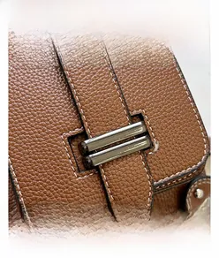 Détail d'un sac à main en cuir marron grainé avec surpiqûres blanches et boucle en métal