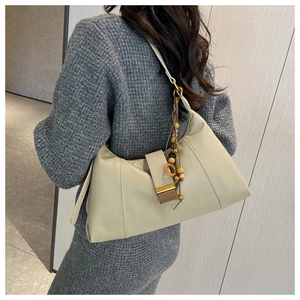 Detail of light green leather shoulder bag with gold clasp and wooden bead tassel