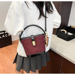 Détail du sac seau matelassé bordeaux avec finition mate et finitions en cuir noir élégant