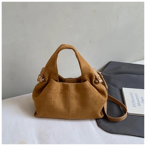 Detail of brown suede tote bag featuring a seamless handle and adjustable strap
