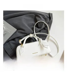Detail view of white leather tote bag with gold lettering and adjustable shoulder strap