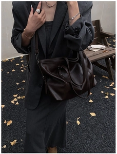 Detailed outdoor shot of dark brown leather tote bag with adjustable shoulder strap