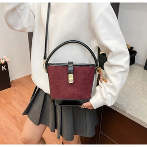 Détail d'un sac seau matelassé bordeaux en daim avec une breloque en perles de bois