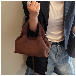 Detail of dark brown matte suede shoulder bag featuring decorative stitching and strap