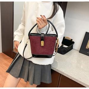 Détail du sac seau matelassé bordeaux avec finitions en cuir noir et fermoir métal