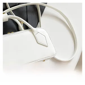 Detail of white glossy leather bag showing gold zipper, rivets and precise stitching