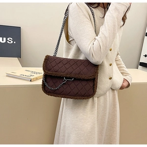 Detail of dark brown quilted shoulder bag with faux shearling trim and silver chain