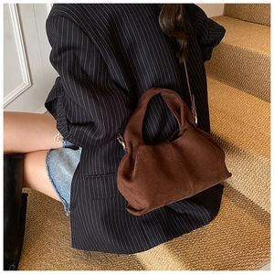 Coffee brown matte suede bucket bag paired with a striped blazer for a stylish look