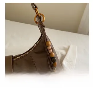 Detail of brown leather bag featuring wood bead charm and antique gold metal rings
