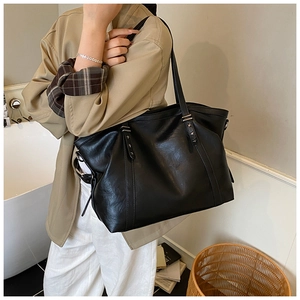 Detail of black tote bag with silver star rivets and premium leather texture on shoulder