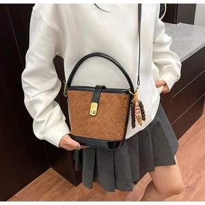 Détail du sac seau en daim matelassé avec bordure en cuir et poignée ronde rigide