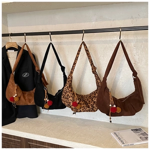 Detail of suede crossbody bags in leopard print and solid colors with fuzzy tassels