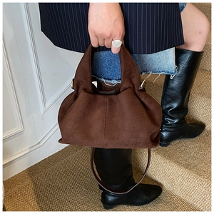 Detail of dark brown cloud bag featuring soft pleated suede texture and leather strap