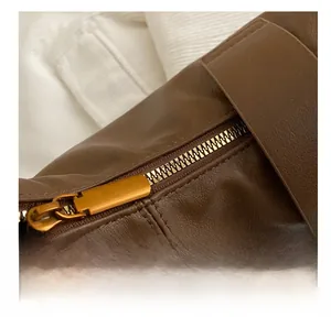 Close-up of smooth gold metal zipper on brown pebble leather tote bag with detail view