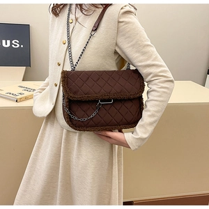 Detail of brown quilted shoulder bag with plush shearling trim and metal chain strap