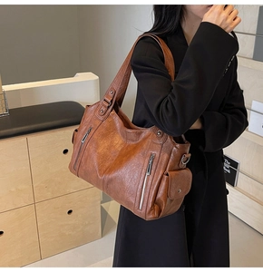 Detail view of retro brown leather tote bag with functional zippers and side flap pocket