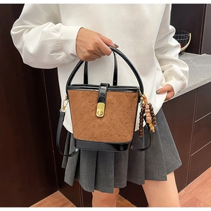 Détail du sac seau matelassé marron avec fermoir doré et pendentif en perles bois
