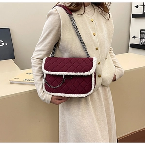 Detail of burgundy quilted bag featuring white fleece trim and silver chain strap