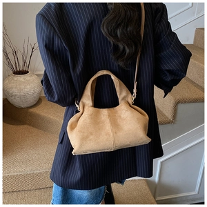 Brown suede slouchy shoulder bag styled with an oversized striped blazer and minimalist background