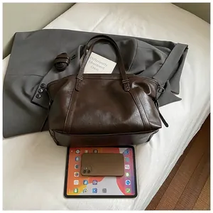 Top view of deep brown tote bag on white sheets showing spacious size for tablets