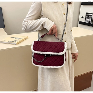 Detail of burgundy quilted shoulder bag with white faux fur trim and metal chain strap