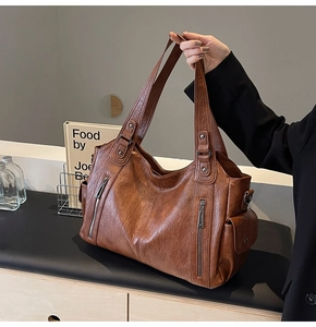 Detail of vintage brown tote bag with leather texture and functional metal zipper accents