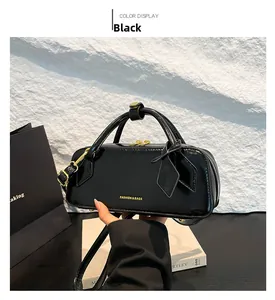 Detail view of glossy black faux leather handbag with golden zipper and logo text