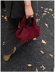 Close-up of matte suede texture and shoulder strap on dark burgundy hobo handbag