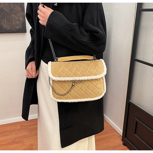 Detail of camel quilted shoulder bag with plush fleece trim worn with black coat