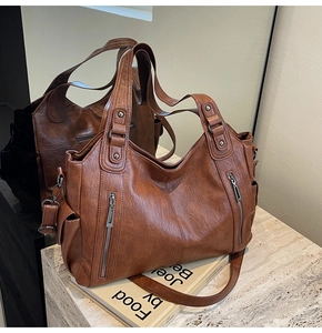 Detail of a brown textured faux leather tote bag with vertical zippers and wide handles