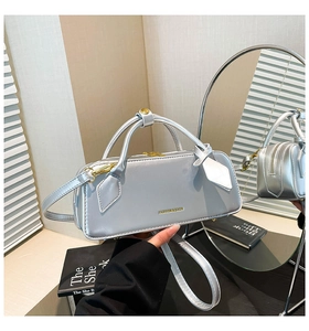 Detail of silver metallic rectangular handbag with FASHION & BAGS logo and gold zipper