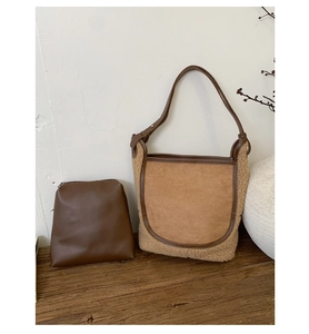 Detail of shearling patchwork bucket bag with leather inner pouch on rustic wood surface