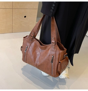 Detail of deep brown tote bag showing pebbled texture and parallel zippers