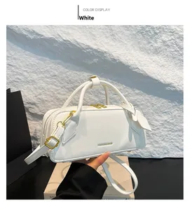 Detailed view of white baguette bag with golden zipper and adjustable shoulder strap