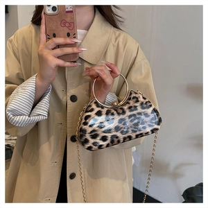 Detail of leopard print evening bag with golden round handle and chain strap on model