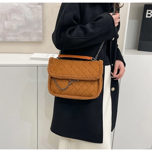 Detail of quilted brown underarm bag with plush trim and chain strap styled on a model