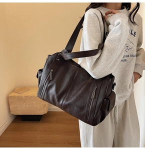 Detail view of large dark brown leather tote bag with vertical zippers and side pockets