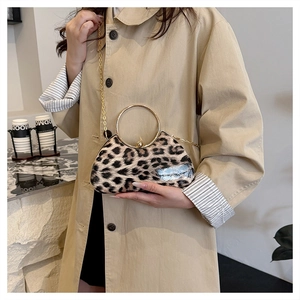 Detail of leopard print clutch featuring a large gold round handle and metal chain strap